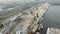Aerial view of port working cranes extracting sand from iron barge and scow on river bank in industrial dirty city in smog
