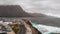 Aerial view of the promenade and coastal stones in the port city of Agaete. Giant misty rocks hanging over the dark