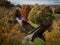 Aerial view of a public park full of trees with a bridge during autumn