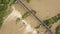 Aerial view of railway metal bridge over dirty river with muddy water in flooding period during heavy rains in spring.