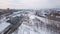 Aerial view of railway station, trains, cars and buildings covered with snow against evening grey sky in winter. Clip