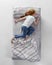 Aerial view of red-headed young sleeping girl in cotton homewear lying in huge gray bed. Concept of health, home