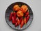 Aerial view of red hot chilis and Bahamian goat peppers on black ceramic plate.
