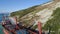 Aerial view of red industrial ship with people on board doing sailor work moored near sea shore. Shot. Big barge on the