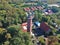 Aerial view at red lighthouse, at baltic sea coast with forest and buildings.