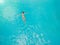 Aerial view of a relaxed young woman in the transparent turquoise sea. Top view of slim woman relaxing in hotel pool