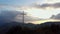 Aerial view of a religious Christian steel cross on a hill in the mountainous countryside,