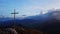 Aerial view of a religious Christian steel cross on a hill in the mountainous countryside, in sunset