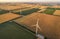 Aerial view of renewable windmills turbines supplying cultivation area with eco power getting energy from wind blowing on vast