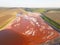 Aerial view of a reservoir full of red toxic sludge