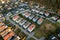 Aerial view of residential houses with red roofs and streets with parked cars in rural town area. Quiet suburbs of a modern