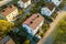 Aerial view of residential houses with red roofs and streets with parked cars in rural town area. Quiet suburbs of a modern