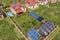 Aerial view of a residential private house with solar panels on roof and wind generator turbine