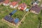 Aerial view of a residential private house with solar panels on roof and wind generator turbine