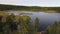 Aerial view rising behind a big spruce tree revealing calm lake and forest