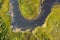 Aerial view of river, green swamp grass, summer landscape. Winding river with overgrown banks, top view