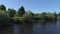 Aerial view of a river in summer village and an old wooden house. Shot. Forest and small house surrounded by green trees