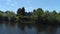 Aerial view of a river in summer village and an old wooden house. Shot. Forest and small house surrounded by green trees