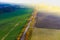 Aerial view of the road in beautiful autumn forest at sunset. Top view of perfect asphalt roadway, trees with orange foliage in