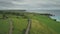 Aerial view road green meadows panning up. Car drives along farmland way in Irish coutryside