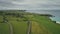 Aerial view road green meadows panning up. Car drives along farmland way in Irish coutryside