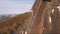 Aerial view of a rock climber climbing a steep cliffs during a sunny winter day.