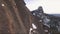 Aerial view of a rock climber climbing a steep cliffs during a sunny winter day.