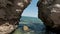 Aerial view of rocks and sandy sea shore, summer and holiday concept. Action. Flying through the stone arch with the