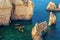 Aerial view of rocky coast in Ponta da Piedade in Lagos, with kayak group in clear ocean water. Portugal. Lagos.