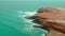 an aerial view of a rocky coastline with a body of water in the foreground and a lone boat in the distance in the distance