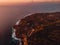 Aerial view of rocky coastline with cliff and ocean at warm sunset. Uluwatu area