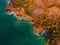 Aerial view of rocky shore with surfers, waves and sunset