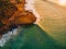 Aerial view of rocky shore with surfers, waves and warm sunset. Drone shot in Bali