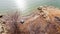 Aerial view rocky shoreline, sandstone cliff with dormant trees and large family tent at Grapevine Lake, Texas, USA