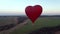 Aerial view romantic balloon flight in the form of a large red heart at sunset.