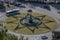 Aerial view of a roundabout with a fountain in the middle with green grass and a design of a star in stone