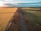 Aerial view of rural road passing through agricultural land in Australian countryside at sunset.