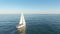 Aerial view of sail yacht sailing at sea near coastline. Blue sea with sun reflections. Drone view - birds eye angle.