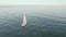 Aerial view of sail yacht sailing at sea near coastline. Blue sea with sun reflections. Drone view - birds eye angle.