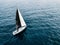 Aerial view of sailing ship yacht with white and black sails at deep open sea