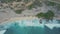 Aerial view of sandy beach with beautiful waves, turquoise ocean water, palms