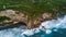 Aerial view of sea rocky coast with surf the waves, Bali, Indonesia, Pura Uluwatu cliff. Waves crushing rocky shore. Seascape,