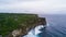 Aerial view of sea rocky coast with surf the waves, Bali, Indonesia, Pura Uluwatu cliff. Waves crushing rocky shore. Seascape,