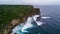 Aerial view of sea rocky coast with surf the waves, Bali, Indonesia, Pura Uluwatu cliff. Waves crushing rocky shore. Seascape,