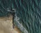 Aerial view of the sea surf on a sandy beach with a stone breakwater.  Top down view of sea waves by drone