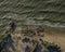 Aerial view of the sea surf on a sandy beach with a stone breakwater.  Top down view of sea waves by drone