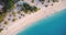 Aerial view of sea waves, umbrellas, green palms on the sandy beach