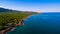 Aerial view of seaside rural cottages surrounded by lush vegetation and a calm seascape view