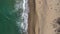 Aerial view of a secluded sandy beach and sea waves