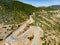 Aerial view of serpentine road snaking between mountains in West Greece. A road full of twists and turns winding sharply up the